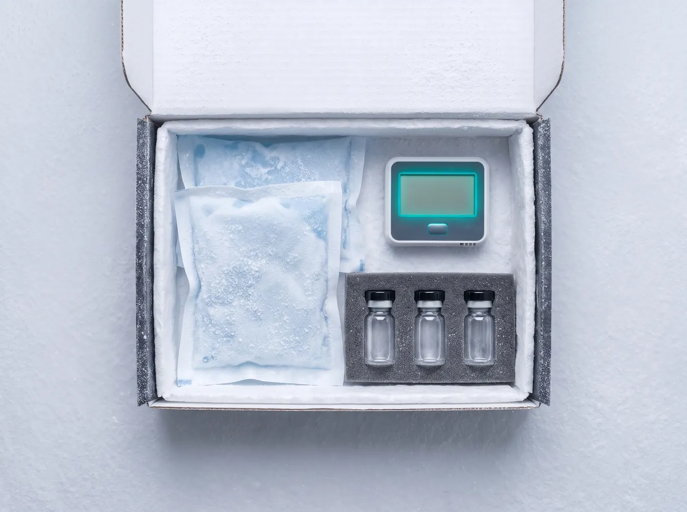 Open parcel with three research vials and a temperature logger